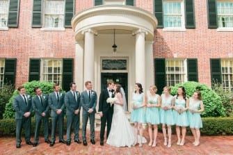 A group of bridesmaids and groomsmen pose in front of the Carolina Inn.