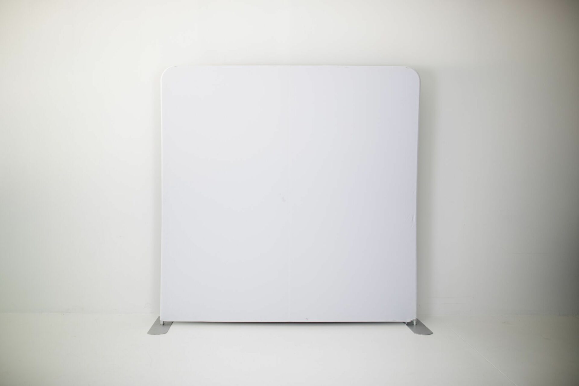 A white backdrop with a metal frame in a white room.