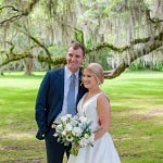 A bride and groom standing in front of a spanish moss covered tree.