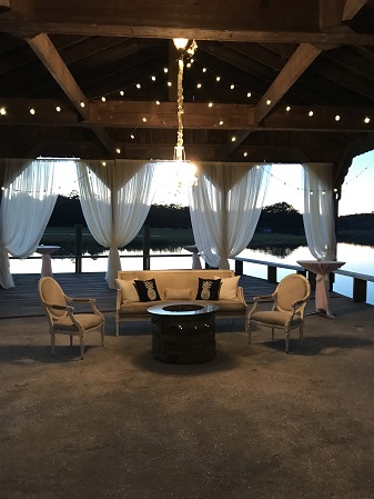 A covered patio with string lights over a lake.