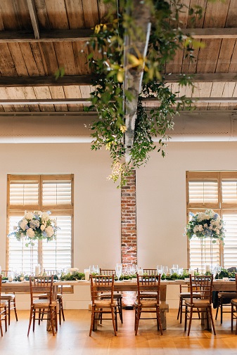 A wedding reception with greenery hanging from the ceiling.
