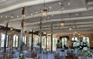 A wedding reception set up in a large room with white tables and chairs.