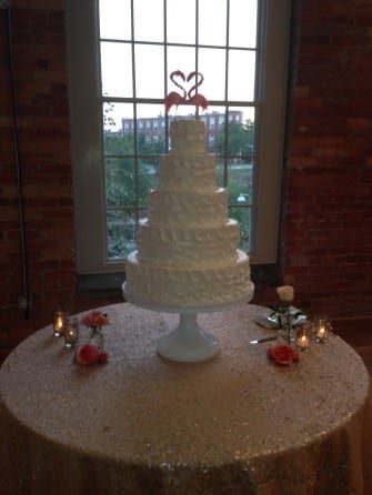 A wedding cake on a table in front of a window.