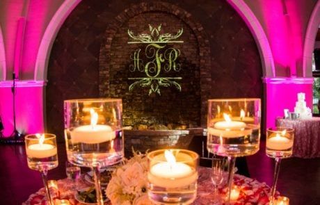 A wedding reception with candles and pink lighting.