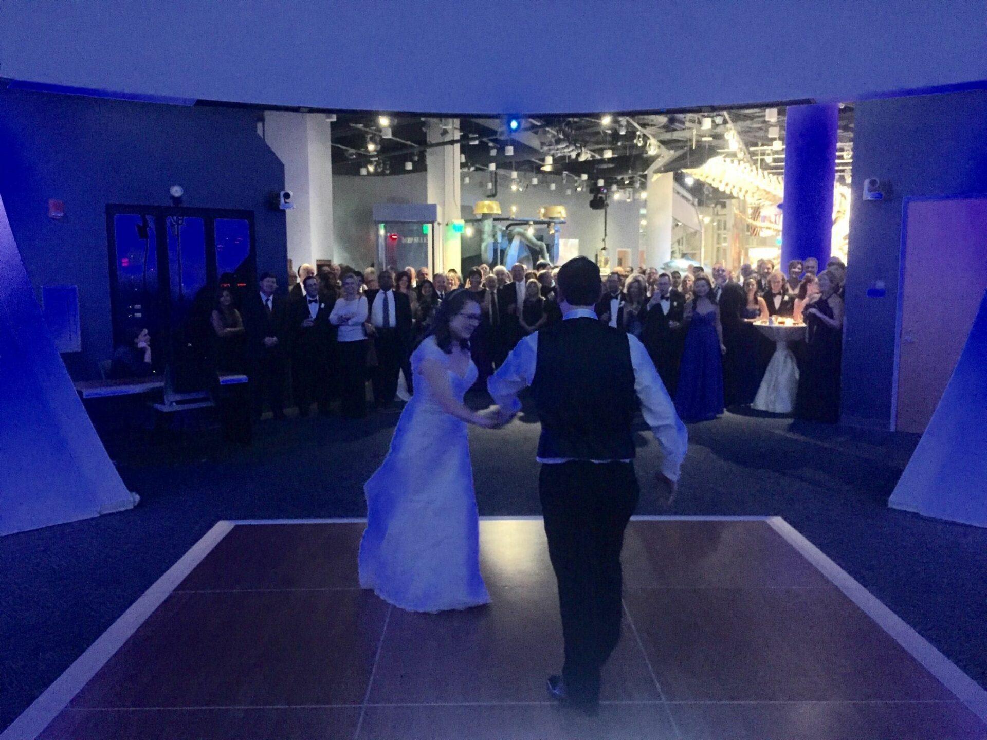 A couple gracefully dances in front of a crowd at their wedding reception, accompanied by the music provided by a Wedding DJ.
