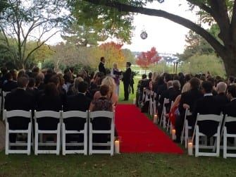 A Fearrington Village wedding ceremony with chairs and a red carpet, set to the tune of a talented wedding DJ.