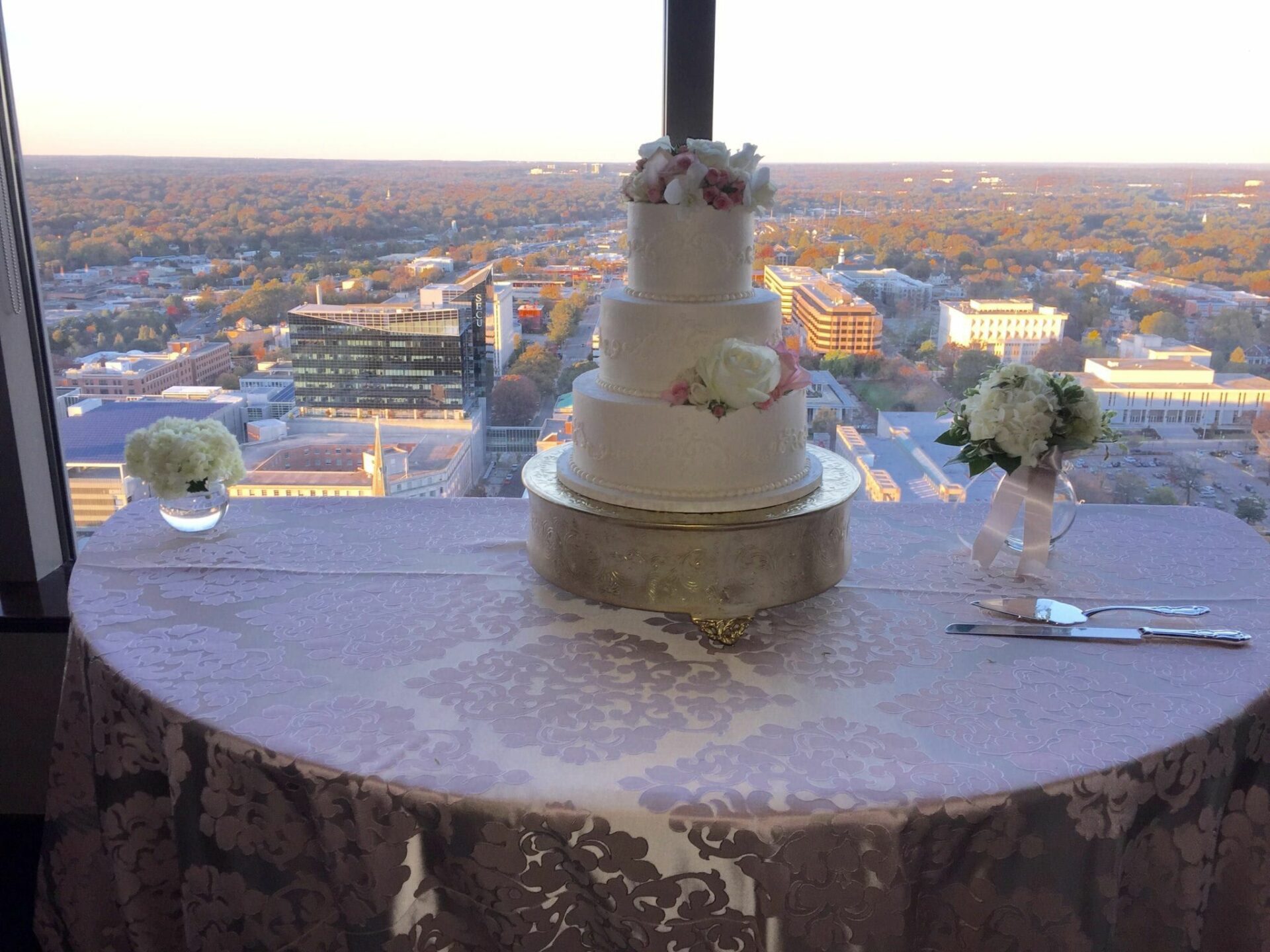 A wedding cake on a table with a view of the city, accompanied by the energetic beats of a Wedding DJ.