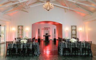 A room with tables and chairs set up for a wedding reception.