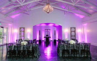 A wedding reception with purple lighting in a large room.
