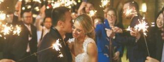 A bride and groom kissing in front of sparklers.