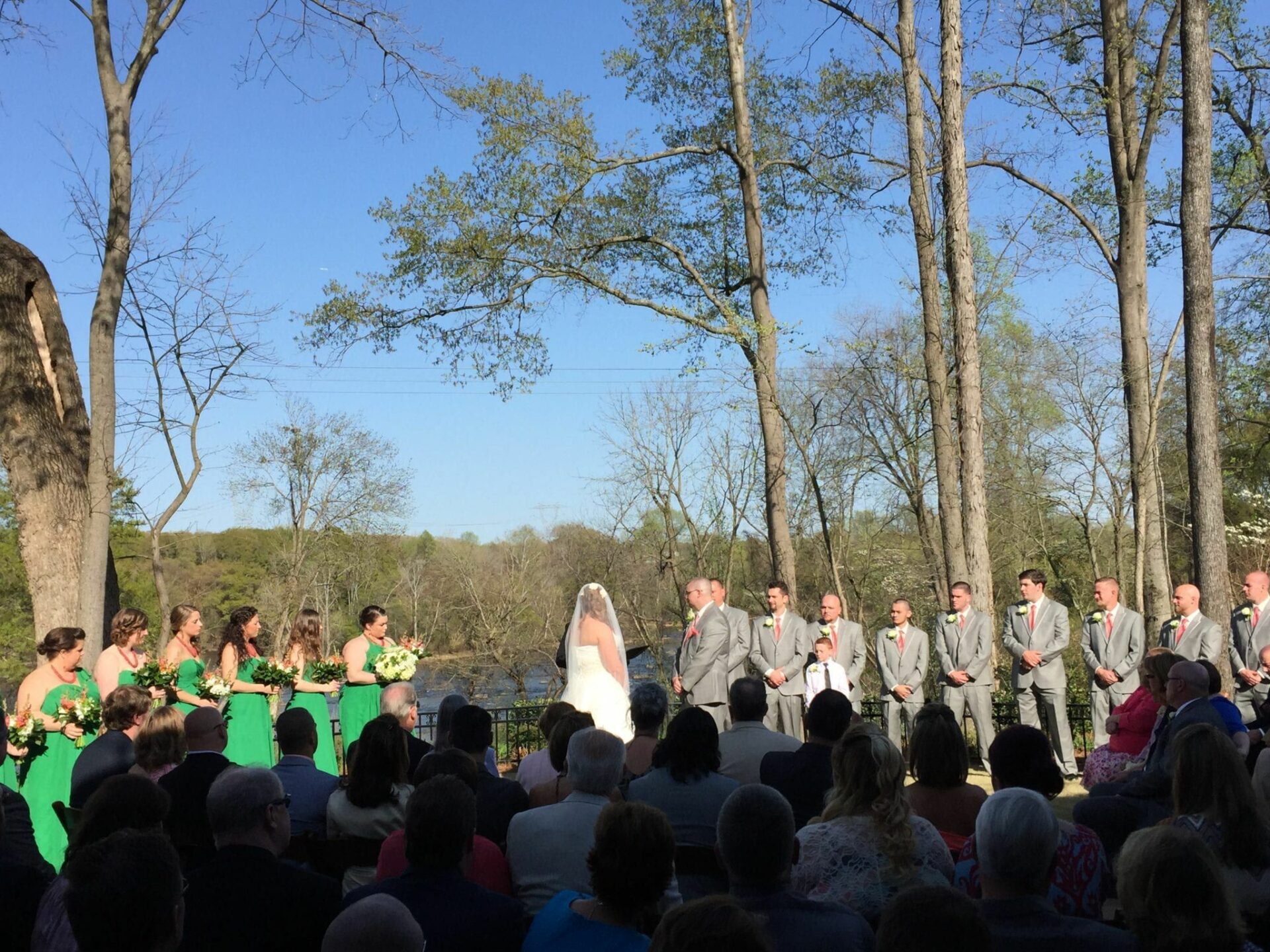 A group of people having a wedding ceremony in front of a tree at Brakefield River Walk.