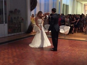 A bride and groom dancing on a wooden floor.