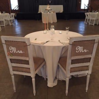Two chairs with "Mr." and "Mrs." written on them are elegantly arranged at a wedding ceremony in Fearrington Village, where a talented wedding DJ sets the perfect atmosphere.