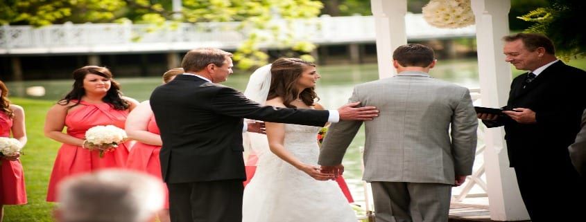 A bride and groom are holding hands during their wedding ceremony.