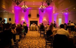A wedding reception with purple lighting in a large room.