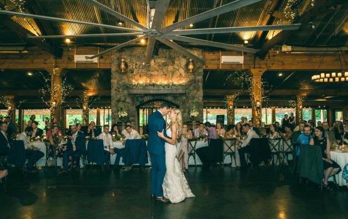 A bride and groom sharing their first dance in a rustic barn.