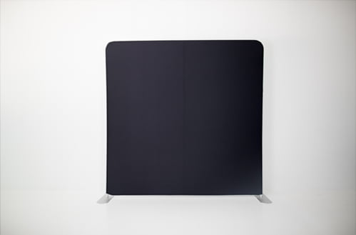 A black screen on a stand against a white wall.