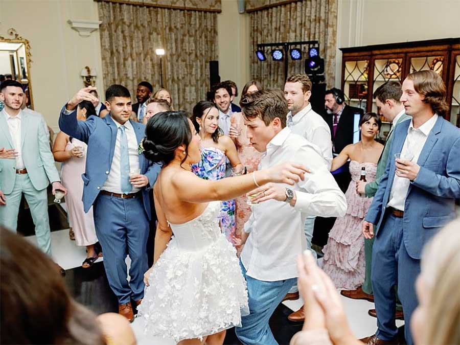 charlotte-duke-mansion-wedding-dance-floor A group of people in formal attire dance and socialize at an indoor event or wedding reception.