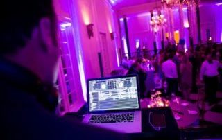 A man is djing at a party with purple lights.