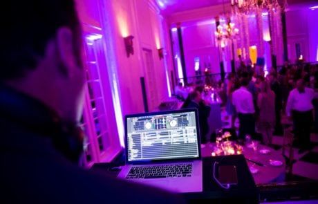 A man is djing at a party with purple lights.