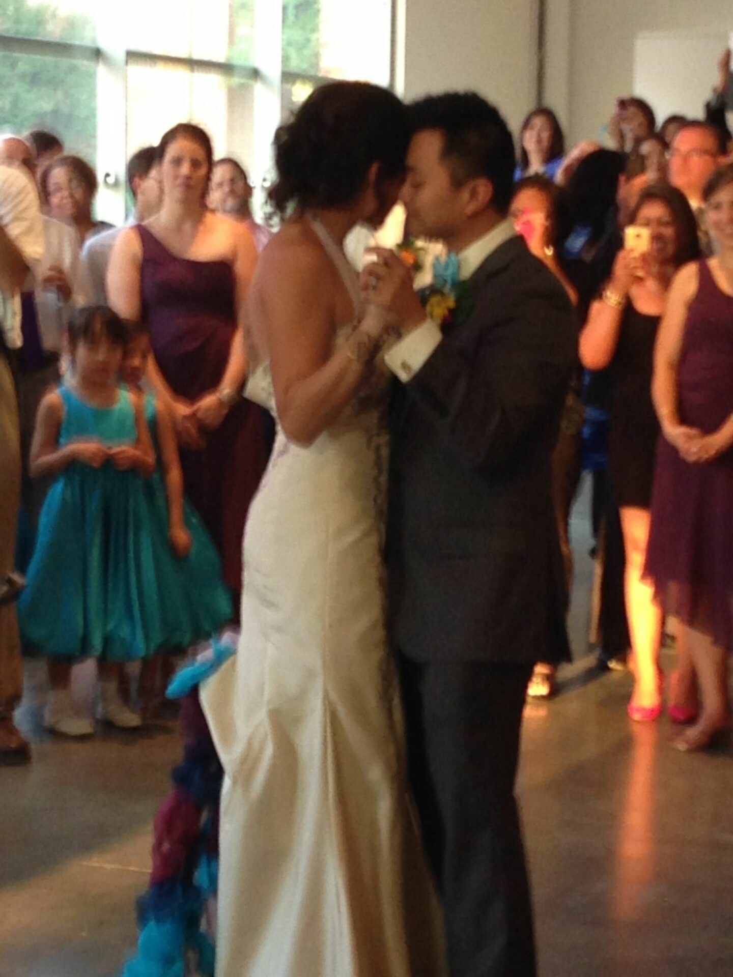 A wedding bride and groom sharing their first dance in front of a crowd.