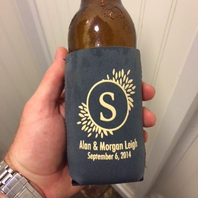 A person holding a bottle of beer with a monogram at a reception.
