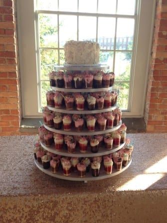 A three tiered cake with cupcakes on it.