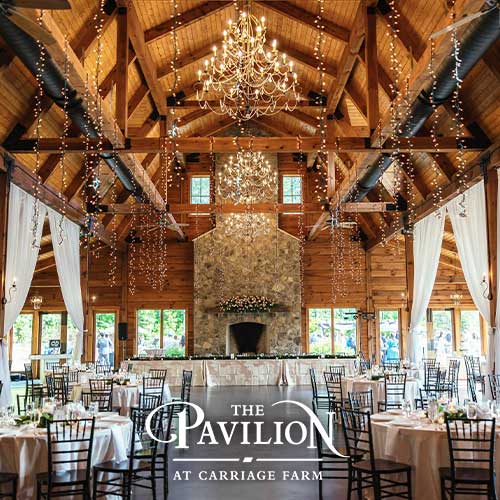A rustic event venue with wooden beams, chandeliers, draped curtains, round tables with white linens, and a stone fireplace. Text reads: "The Pavilion at Carriage Farm.