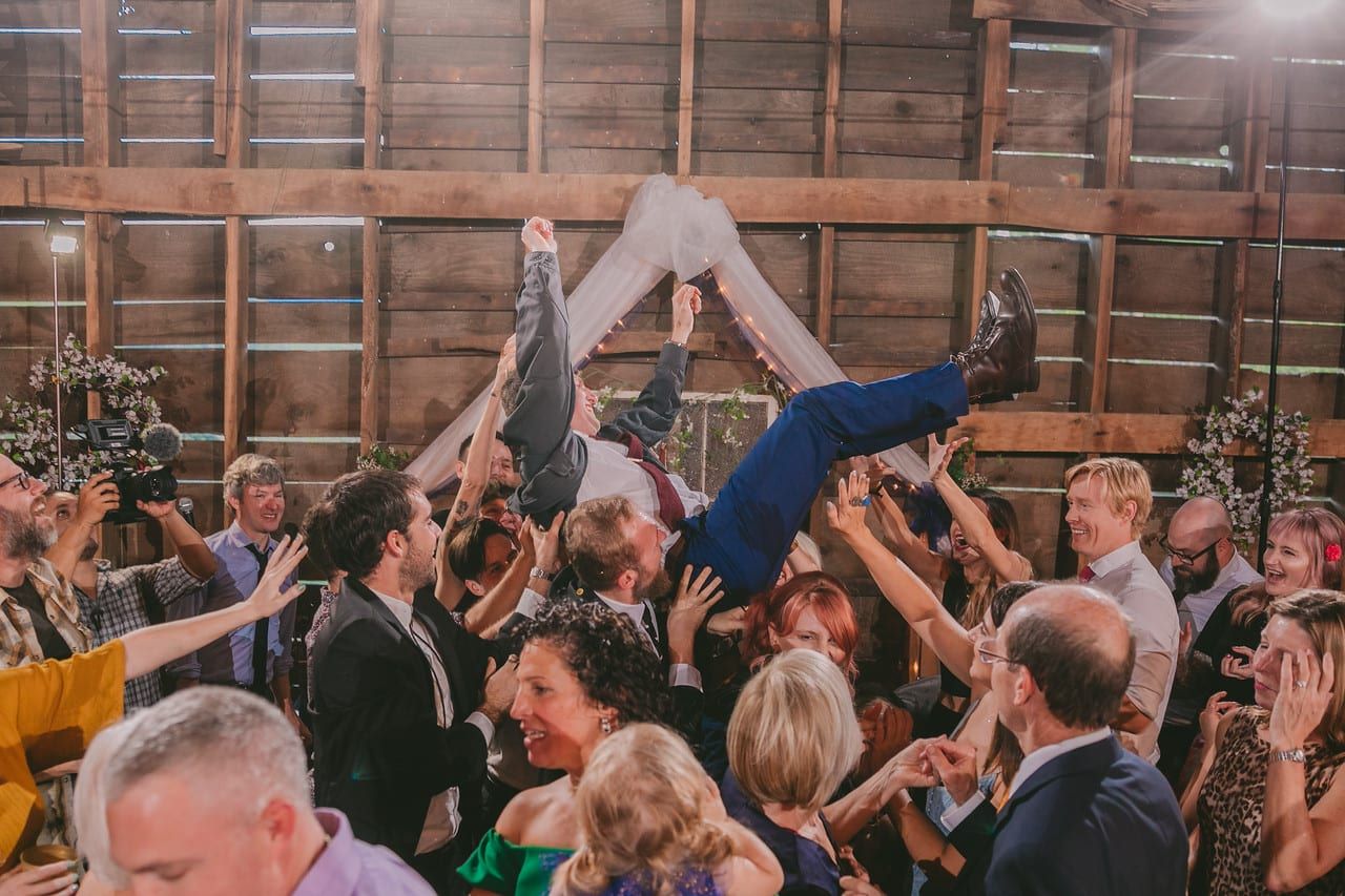 A group of people dancing in a barn at a wedding.