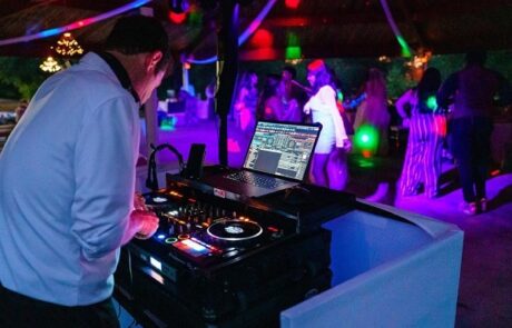 A man is djing at a party under a tent.