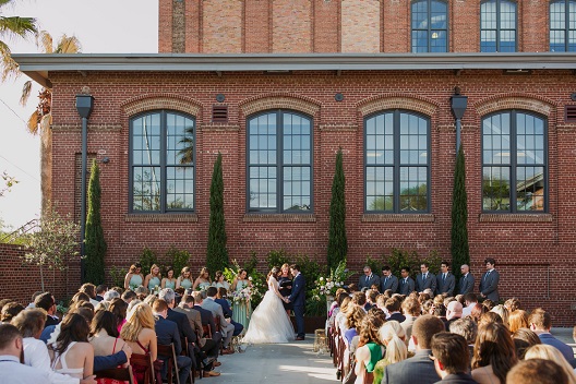 A wedding ceremony in front of a brick building.