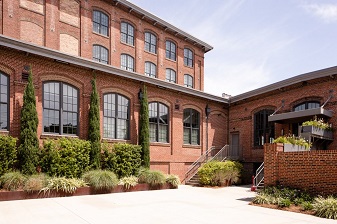 A brick building with large windows and plants.