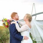 A bride and groom posing in front of a bridge.