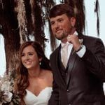 A bride and groom standing under a tree.