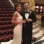 A bride and groom posing in front of a staircase.