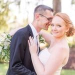 A bride and groom hugging in front of a tree.