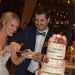 A bride and groom cutting into their wedding cake.