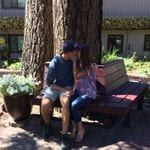 A couple sitting on a bench in front of a building.