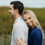 A couple embracing in a field near the ocean.