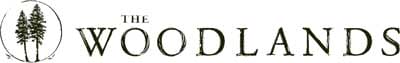 Logo for "The Woodlands" featuring two pine trees inside a circle to the left of the text.