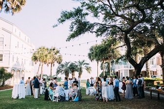 A wedding reception on the lawn with palm trees in the background.